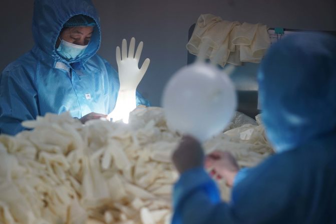Workers check sterile medical gloves at a latex-product manufacturer in Nanjing, China, on February 6, 2020.