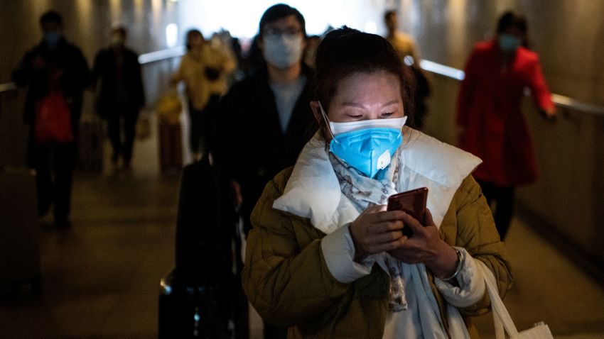 Passengers wearing protective face masks arrive at the Shanghai South railway station in Shanghai on February 9, 2020.