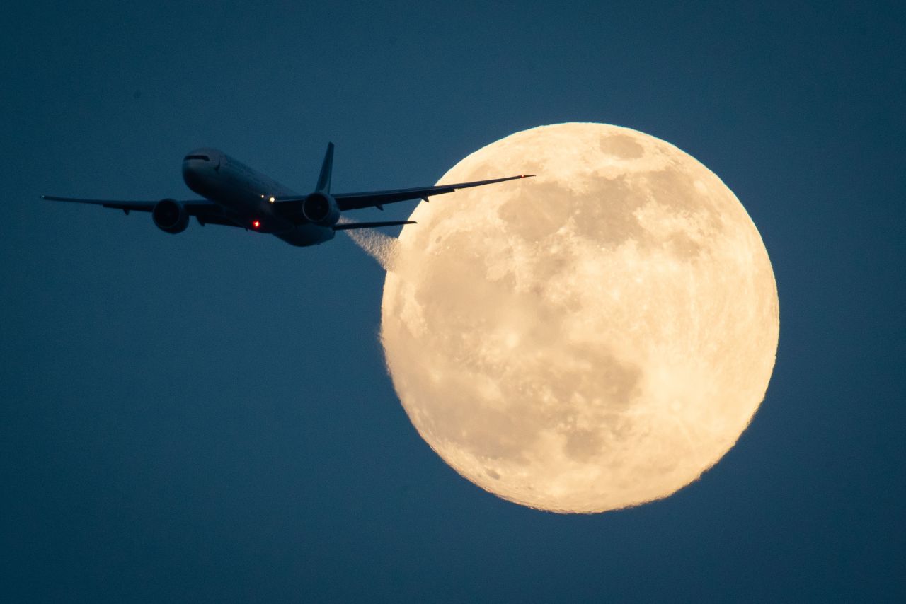 A plane passes the moon as seen from London.