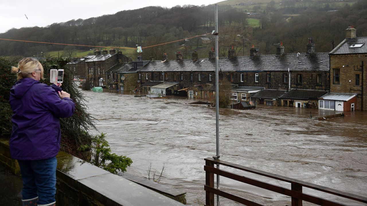 A woman photographs flooded houses in Mytholmroyd, northern England  after the River Calder burst its banks. 