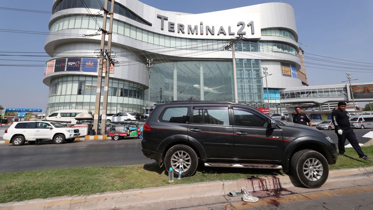 Thai rescue teams walk pass a shooting victim's vehicle outside Terminal 21 Korat mall.