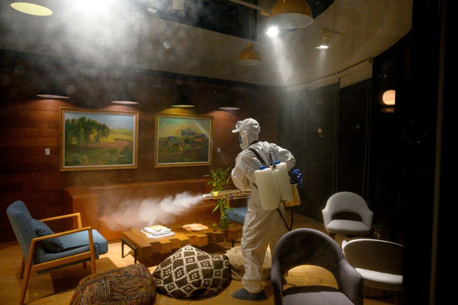 A worker wearing a protective suit uses a machine to disinfect a business establishment in Shanghai, China, on February 9.