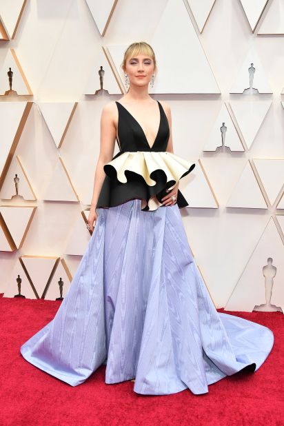 Best Actress nominee  Saoirse Ronan is in a custom Gucci gown featuring a V-neck bodice made of the black satin left over from her BAFTAs gown, with a ruffled waist detailing. The bottom of the dress is a pale lilac skirt. 