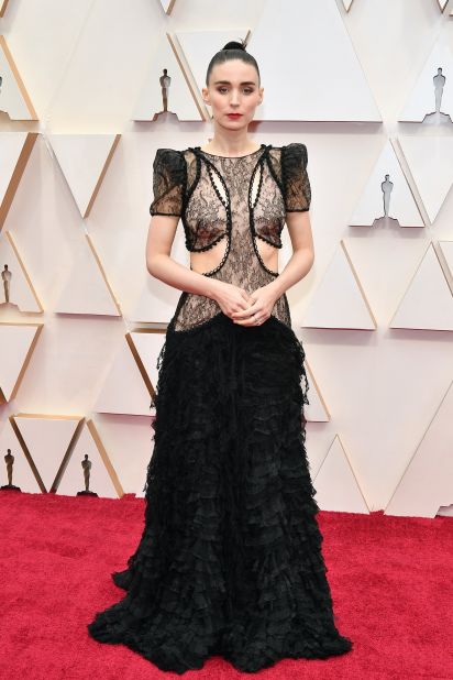 Rooney is dressed in a custom cascading black lace gown by Alexander McQueen, with cutout semi-sheer lace bodice and structured puff shoulders.