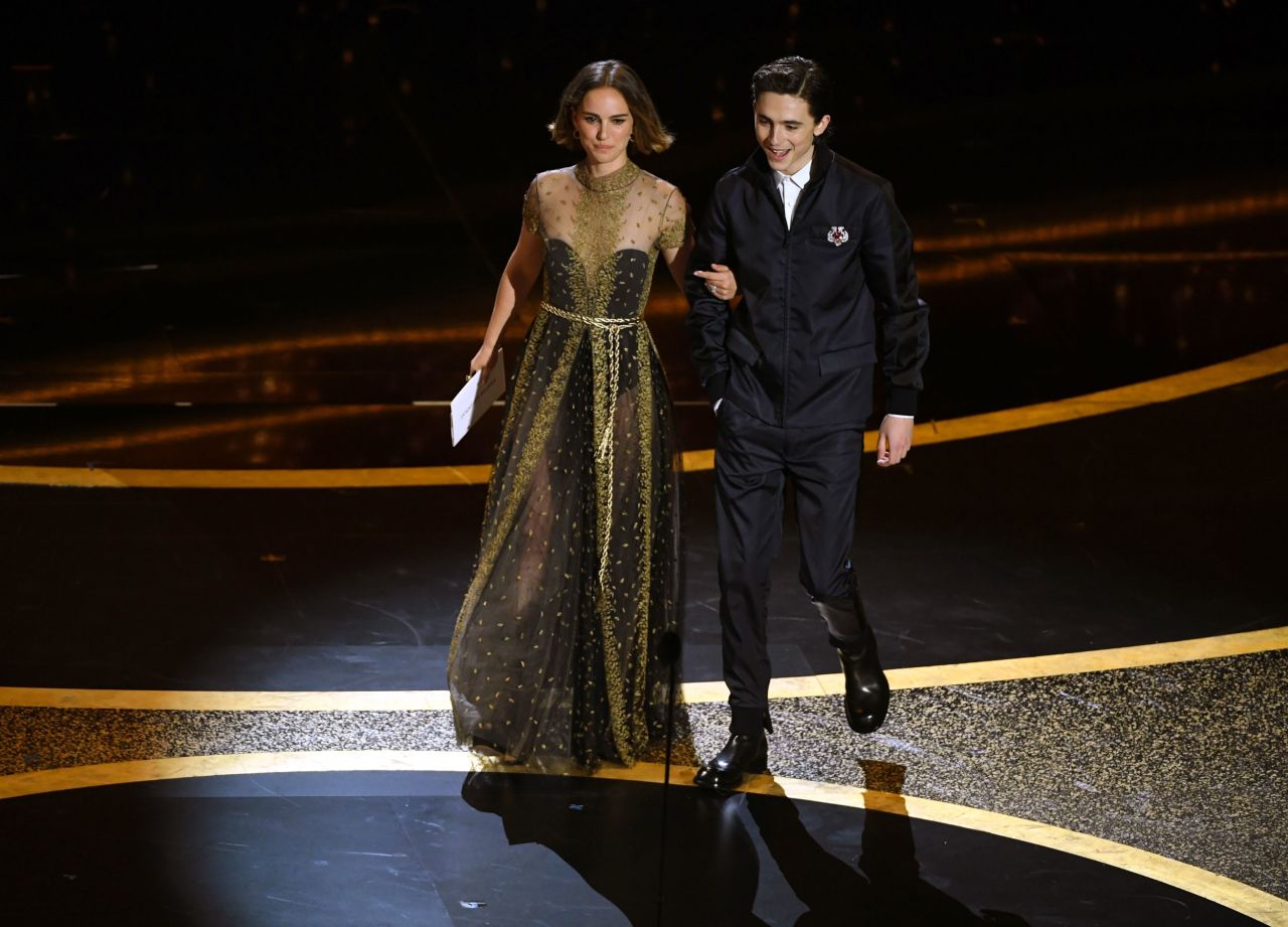 Presenters Natalie Portman and Timothée Chalamet walk on stage.