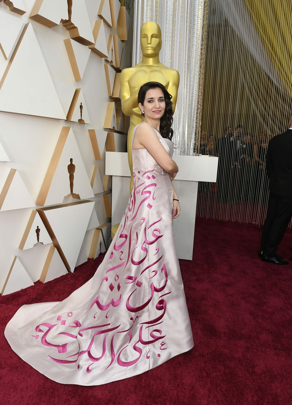 Syrian director Waad al-Kateab wears a message embroidered in Arabic on her gown