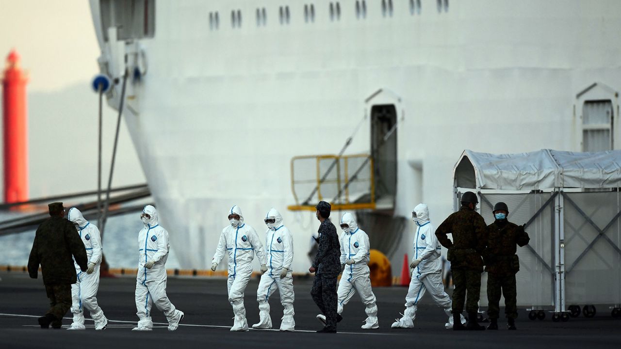 People wearing protective suits walk from the Diamond Princess cruise ship, with around 3,600 people quarantined onboard due to fears of the new coronavirus, at the Daikoku Pier Cruise Terminal in Yokohama port on February 10, 2020. - Around 60 more people on board the quarantined Diamond Princess cruise ship moored off Japan have been diagnosed with novel coronavirus, the country's national broadcaster said on February 10, raising the number of infected passengers and crew to around 130. (Photo by CHARLY TRIBALLEAU / AFP) (Photo by CHARLY TRIBALLEAU/AFP via Getty Images)