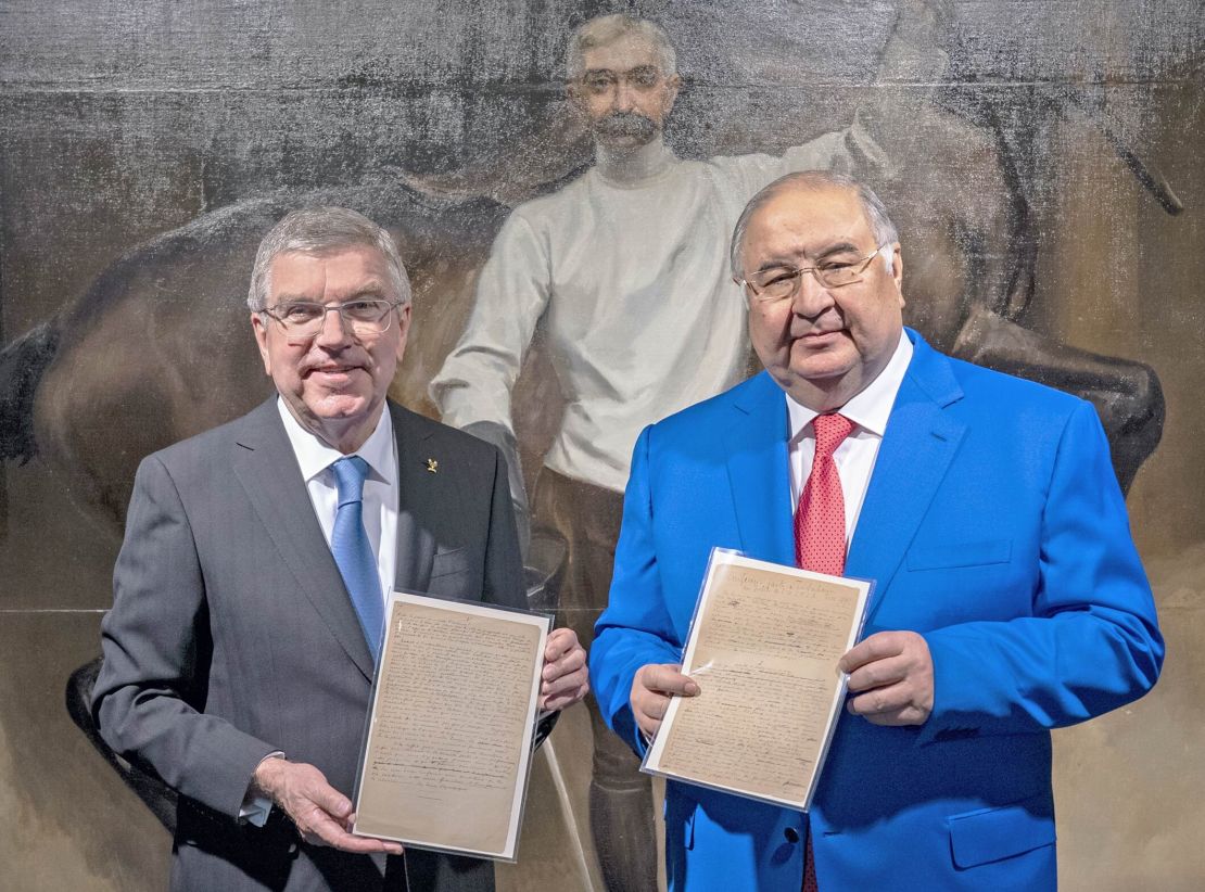 Usmanov (right) and Bach pose with a copy of the original Olympic manifesto.