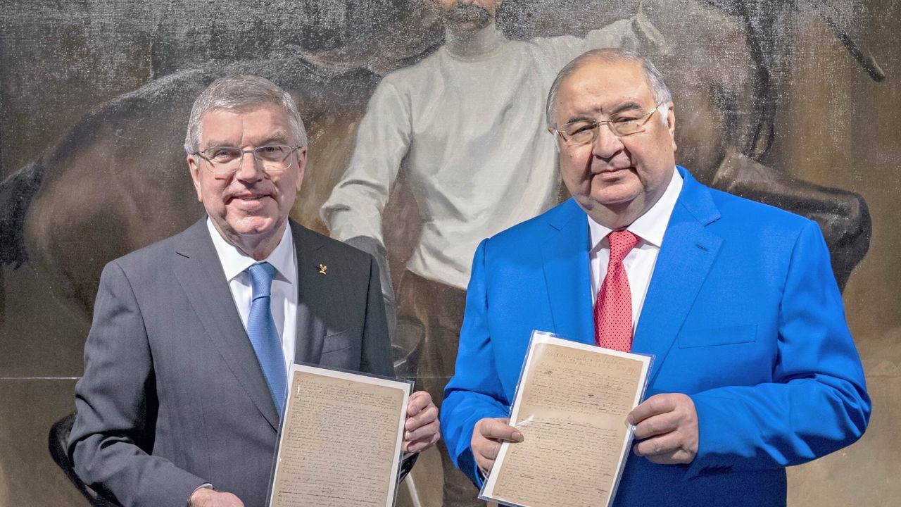 Usmanov (right) and Bach pose with a copy of the original Olympic manifesto.