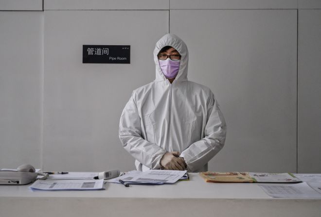 A worker wears a protective suit as he waits to screen people entering an office building in Beijing on February 10. China's workforce is <a href="index.php?page=&url=https%3A%2F%2Fedition.cnn.com%2F2020%2F02%2F10%2Fbusiness%2Fchina-companies-return-to-work-coronavirus%2Findex.html" target="_blank">slowly coming back to work</a> after the coronavirus outbreak forced many parts of the country to extend the Lunar New Year holiday by more than a week.
