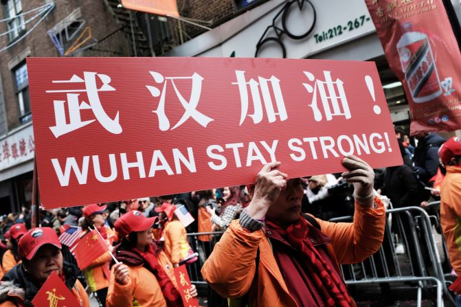 People participating in a Lunar New Year Parade in New York City hold signs reading, "Wuhan stay strong!" on February 9, 2020.