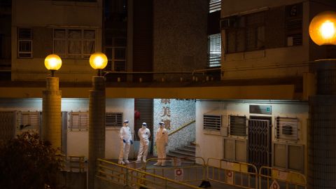 Officials wearing protective gear stand guard outside an entrance to the Hong Mei House residential building.