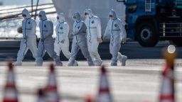 YOKOHAMA, JAPAN - FEBRUARY 11: Emergency workers in protective clothing walk from the Diamond Princess cruise ship as it sits docked at Daikoku Pier where it is being resupplied and newly diagnosed coronavirus cases taken for treatment as it remains in quarantine after a number of the 3,700 people on board were diagnosed with coronavirus, on February 11, 2020 in Yokohama, Japan. 130 passengers are now confirmed to be infected with coronavirus as Japanese authorities continue treating people on board. The new cases bring the total number of infections to 156 in Japan, the largest number outside of China. (Photo by Carl Court/Getty Images)