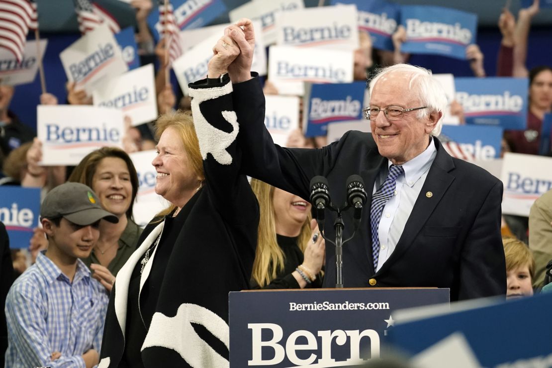 Sanders holds the hand of his spouse Jane O'Meara Sanders as he takes the stage during a primary night event on February 11, 2020 in Manchester, New Hampshire. 