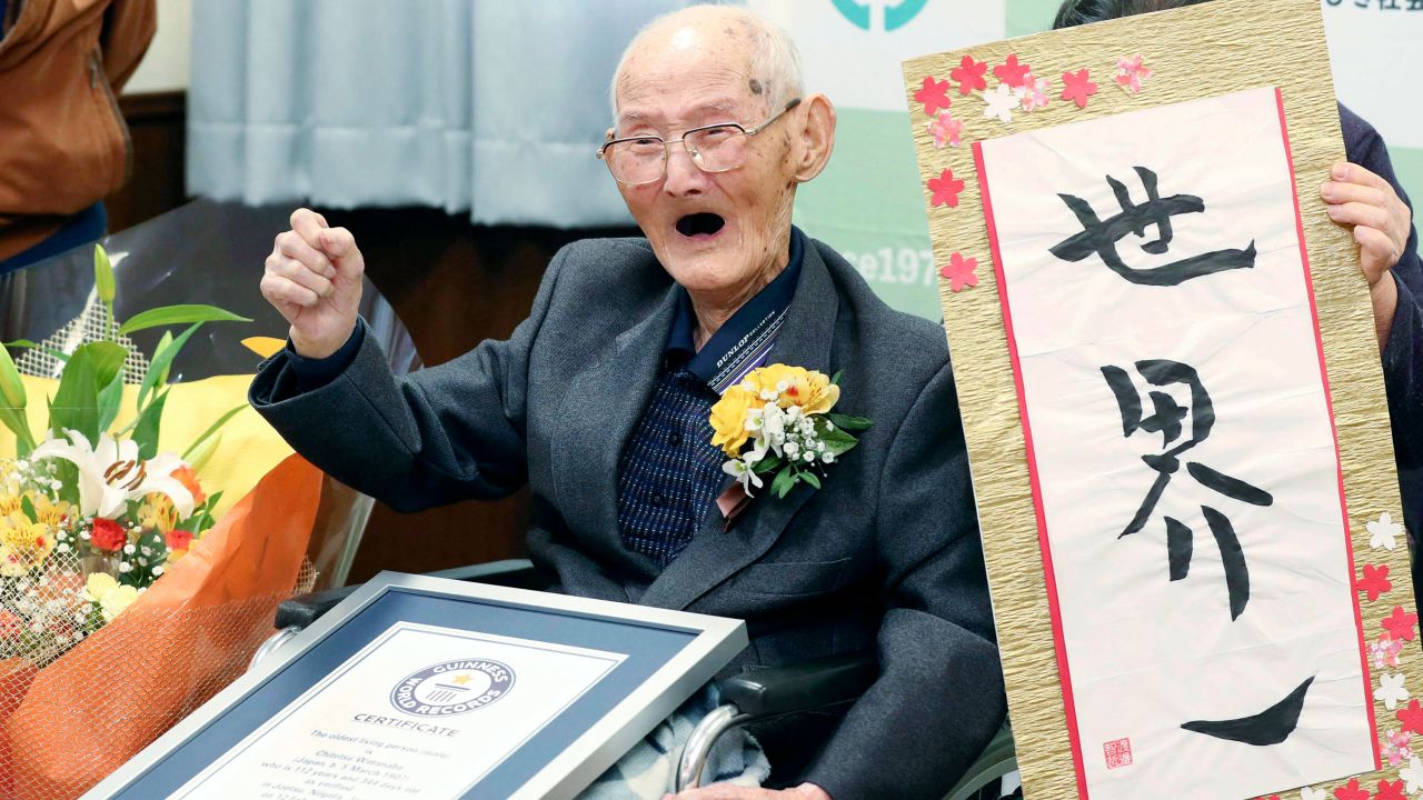 Chitetsu Watanabe, 112, poses next to the calligraphy he wrote after being awarded as the world's oldest living male by Guinness World Records.