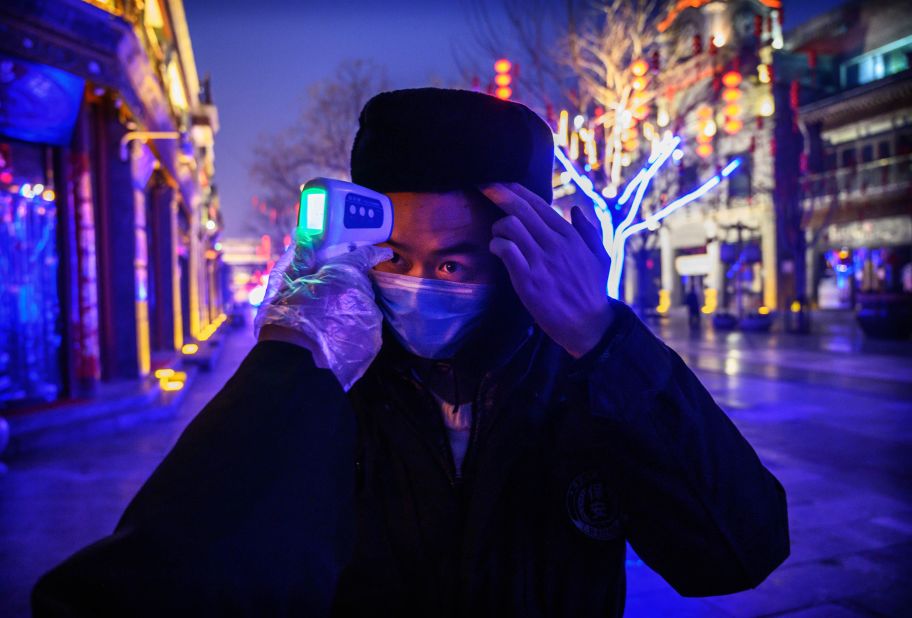 A worker has his temperature checked on a shuttered commercial street in Beijing on February 12.