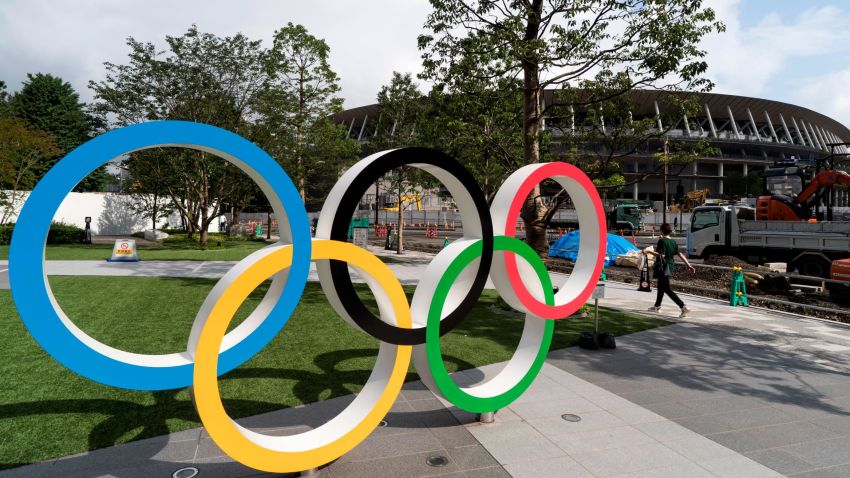 TOKYO, JAPAN - JULY 24: A woman walks past the Olympic rings displayed in front of the New National Stadium, the main venue for the Tokyo 2020 Olympic and Paralympic Games, under construction on July 24, 2019 in Tokyo, Japan. (Photo by Tomohiro Ohsumi/Getty Images)