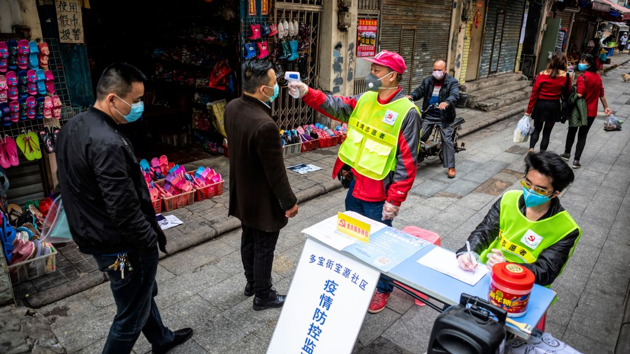 A worker taking pedestrians' body temperatures at a roadblock in Guangzhou this month.