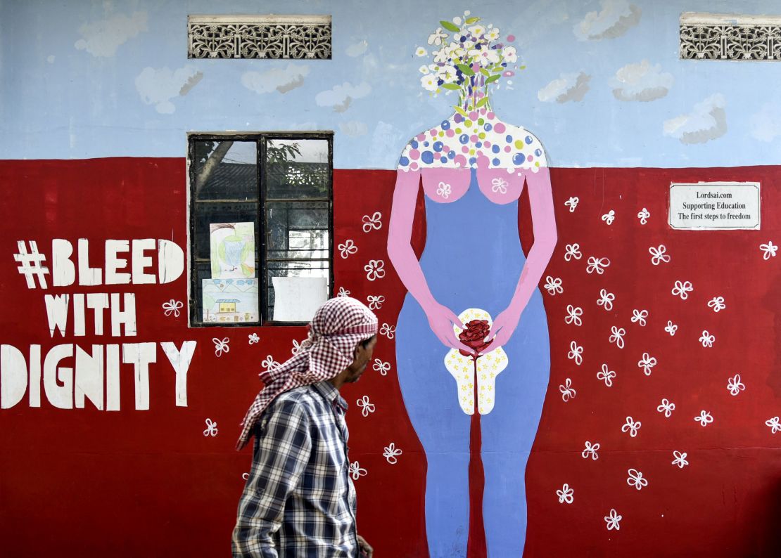 A man walks past a wall painting about female menstruation at a school for underprivileged children on Menstrual Hygiene Day in Guwahati on May 28, 2019. 