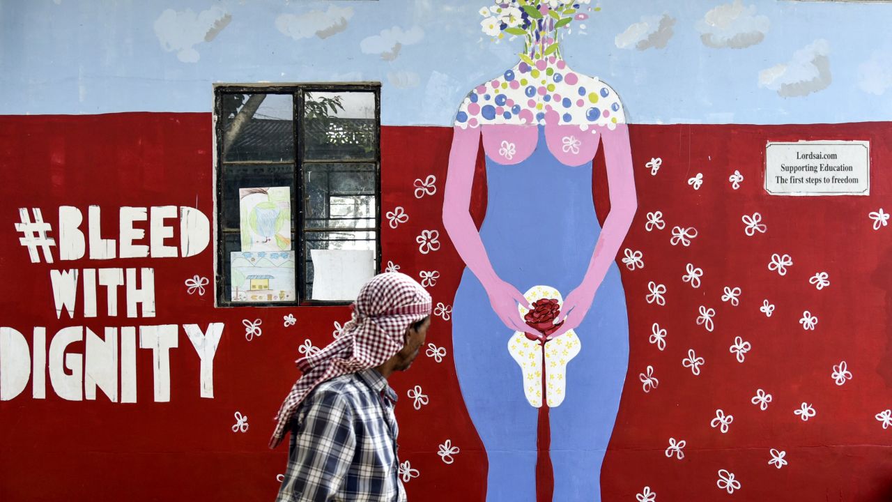 A man walks past a wall painting about female menstruation at a school for underprivileged children on Menstrual Hygiene Day in Guwahati on May 28, 2019.