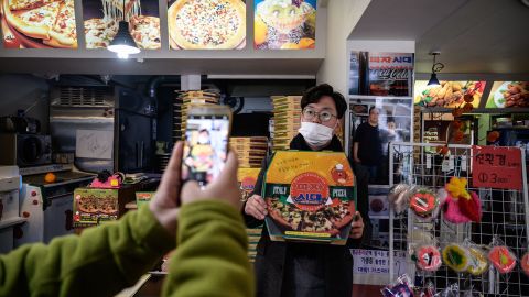 A customer poses before a photo of film director Bong Joon-ho at the 'Sky Pizza' restaurant in Seoul on February 13, 2020. - Locations featured in the South Korea's Oscar-winning "Parasite" are bracing for a boom in customers following the film's success. (Photo by Ed JONES / AFP) (Photo by ED JONES/AFP via Getty Images)