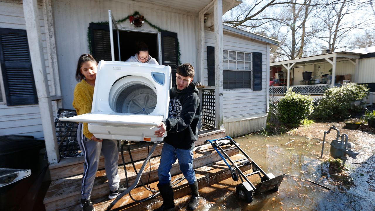 Alondra Rodriguez, left, her brother Mario Vargas and their aunt carry a washing machine from Vargas' mother's mobile home in Ridgeland, near Jackson, as the Pearl River rose Friday.