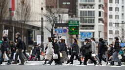 Pedestrians wearing protective masks cross a road in the Ginza area in Tokyo, Japan, on Saturday, Feb. 15, 2020.