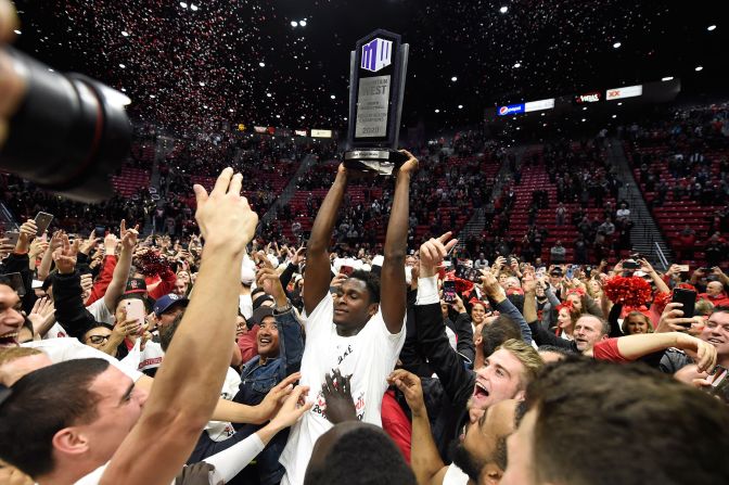 San Diego State forward Joel Mensah holds up the Mountain West Championship trophy after the team defeated New Mexico 89-52 in an NCAA college basketball game, February 11 in San Diego.