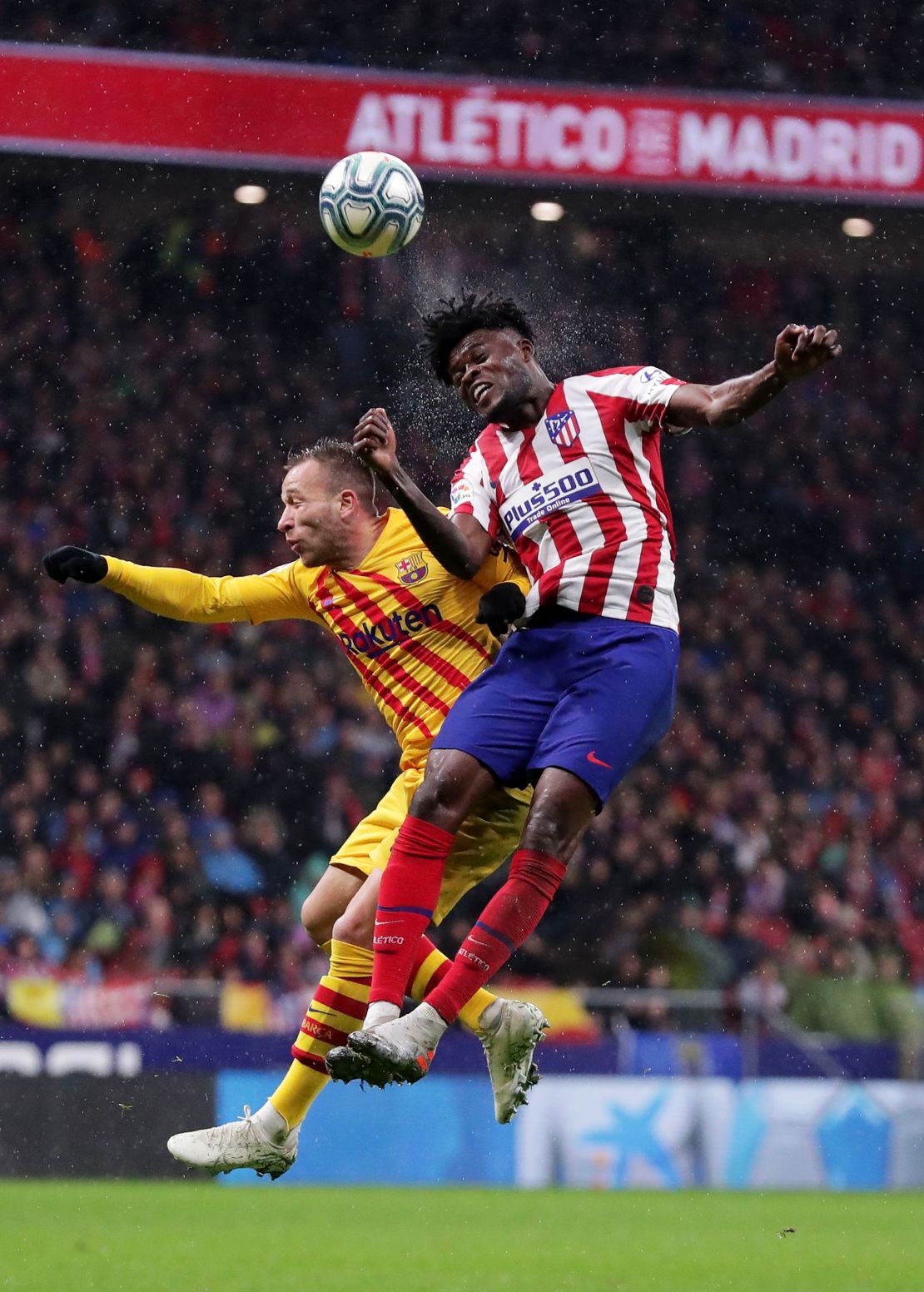 Thomas Partey of Atletico Madrid (R) and Arthur of FC Barcelona jump for the ball.
