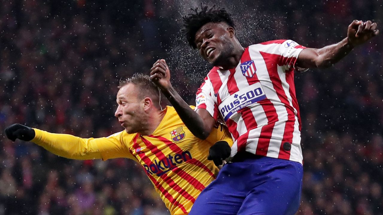 Thomas Partey of Atletico Madrid (R) and Arthur of FC Barcelona jump for the ball.