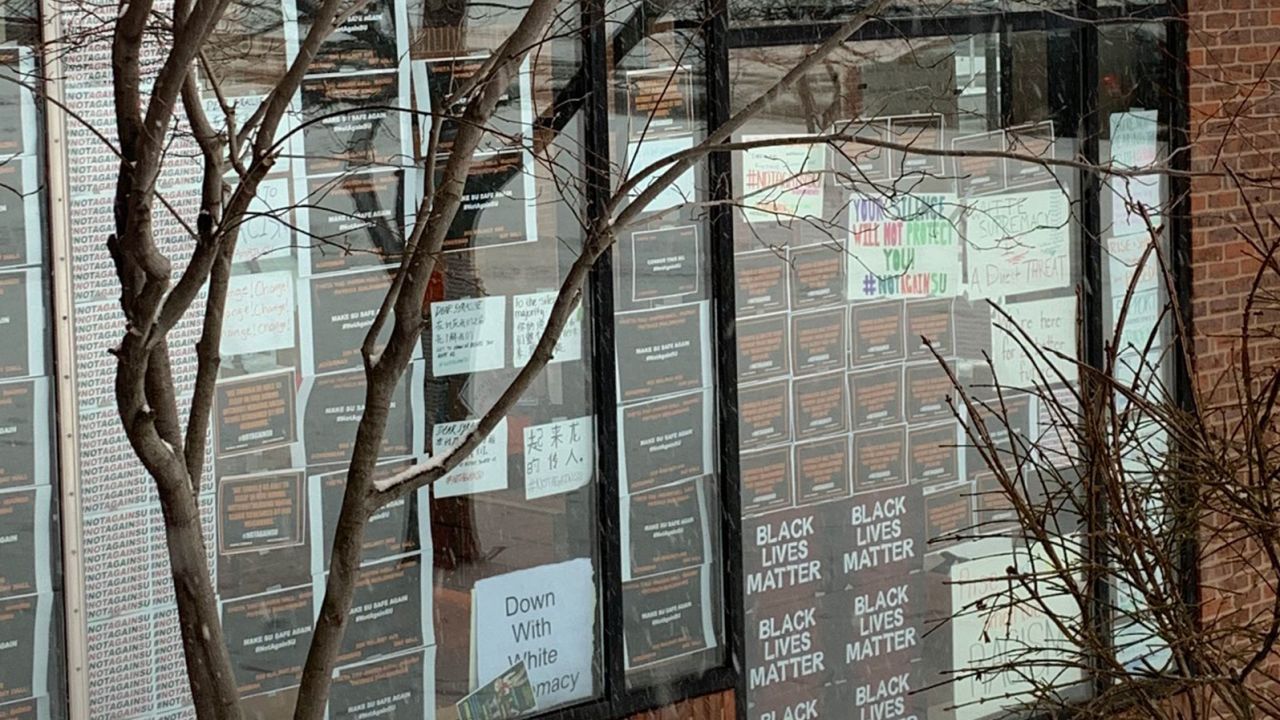 Students put up posters in Crouse-Hinds Hall protesting racist incidents on campus.