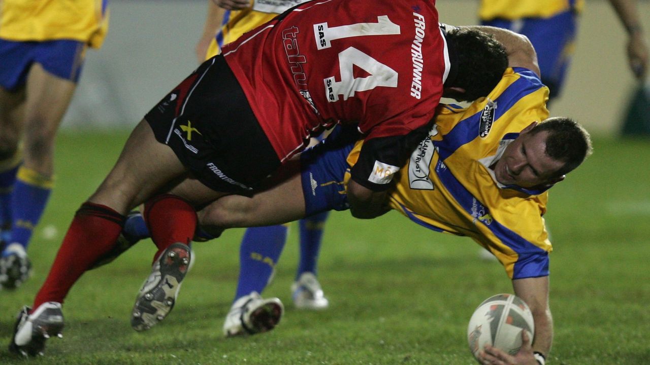 AUCKLAND, NEW ZEALAND - SEPTEMBER 18:  Rowan Baxter of the Lions tackled by Clinton Fraser (L) during the NZRL National Premiership Bartercard Cup Grand Final league match between the Auckland Lions and Canterbury Bulls played at Mount Smart Stadium on September 18, 2006 in Auckland New Zealand.  (Photo by Ross Land/Getty Images)