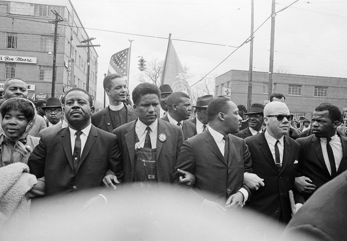 Martin Luther King, Jr. locks arms with his aides as he leads a march to the courthouse in Montgomery, Alabama, on March 17, 1965. John Lewis is at far right. 