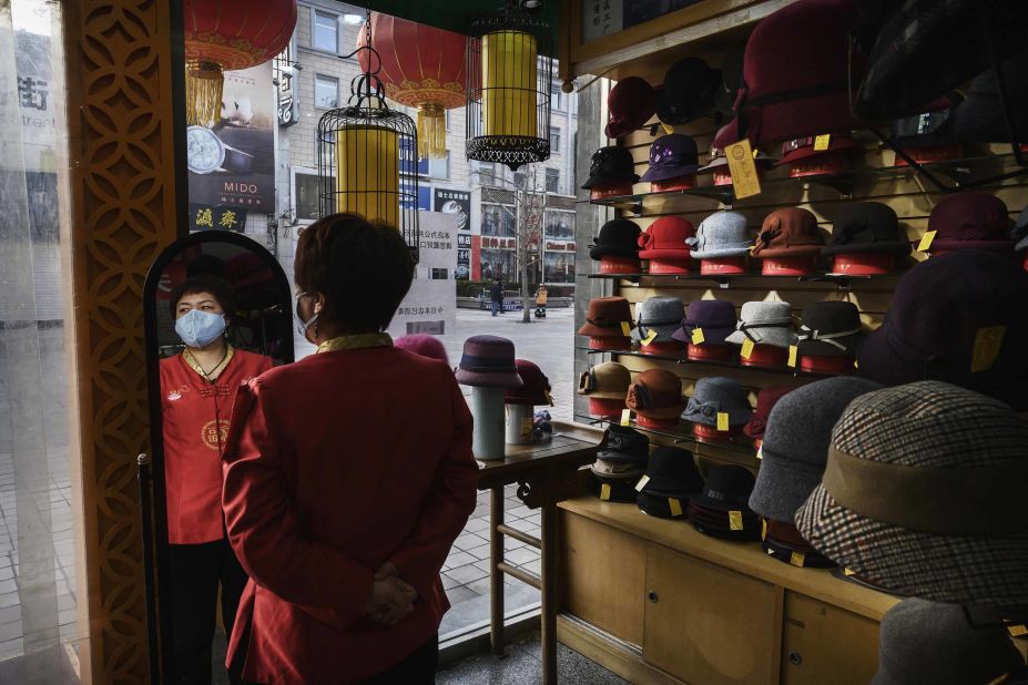 A sales clerk wears a mask as she waits for customers at a hat shop in Beijing on February 18, 2020.