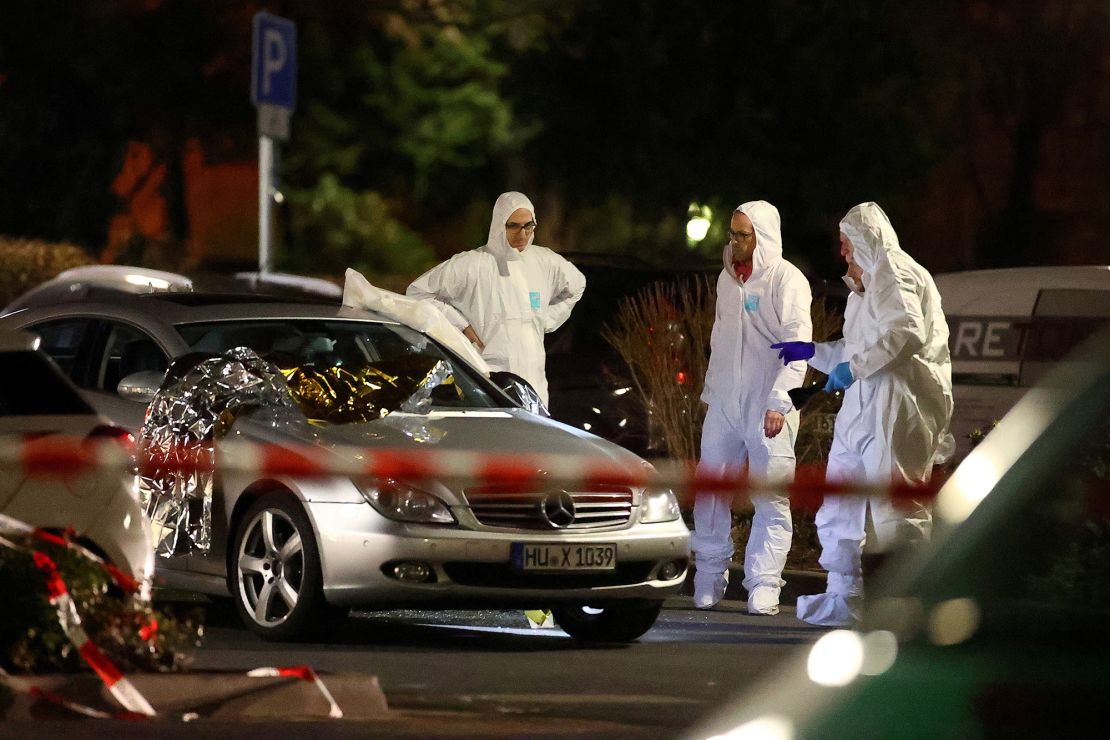 Forensic experts work around a damaged car after the attack in Hanau.