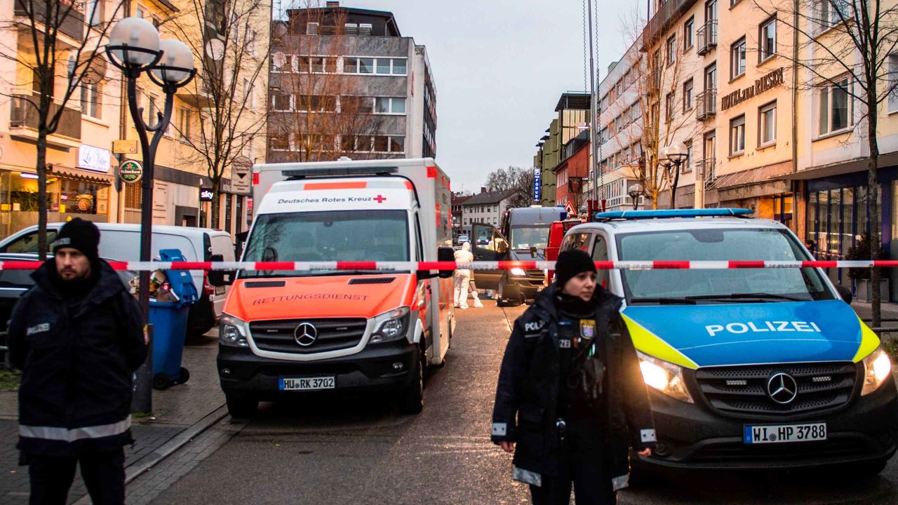 Police, emergency services and forensic police are seen behind a police cordon near a bar (L) in the centre of Hanau, near Frankfurt am Main, western Germany, on February 20, 2020, after at least nine people were killed in two shootings late on February 19. - At least nine people were killed in shootings targeting shisha bars in Germany that sparked a huge manhunt overnight before the suspected gunman was found dead in his home early on February 20. The attacks occurred at two bars in Hanau, about 20 kilometres (12 miles) from Frankfurt, where armed police quickly fanned out and police helicopters roamed the sky looking for those responsible for the bloodshed. Police in the central state of Hesse said the likely perpetrator had been found at his home in Hanau after they located a getaway vehicle seen by witnesses. Another body was also discovered at the property. German counter-terror prosecutors said on February 20 they had taken over the investigation into two linked shootings. (Photo by Thomas Lohnes / AFP) (Photo by THOMAS LOHNES/AFP via Getty Images)