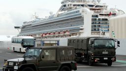 A bus carrying the passengers from the quarantined Diamond Princess cruise ship escorted by Japan Self Defense Forces vehicles leaving a port in Yokohama, near Tokyo, Thursday, Feb. 20, 2020. Passengers tested negative for COVID-19 started disembarking since Wednesday. (AP Photo/Eugene Hoshiko)