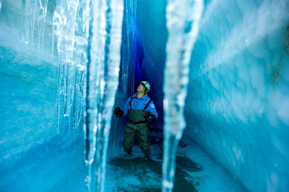 Pugh examines a glacial tunnel where stalactites hang from the roof. 