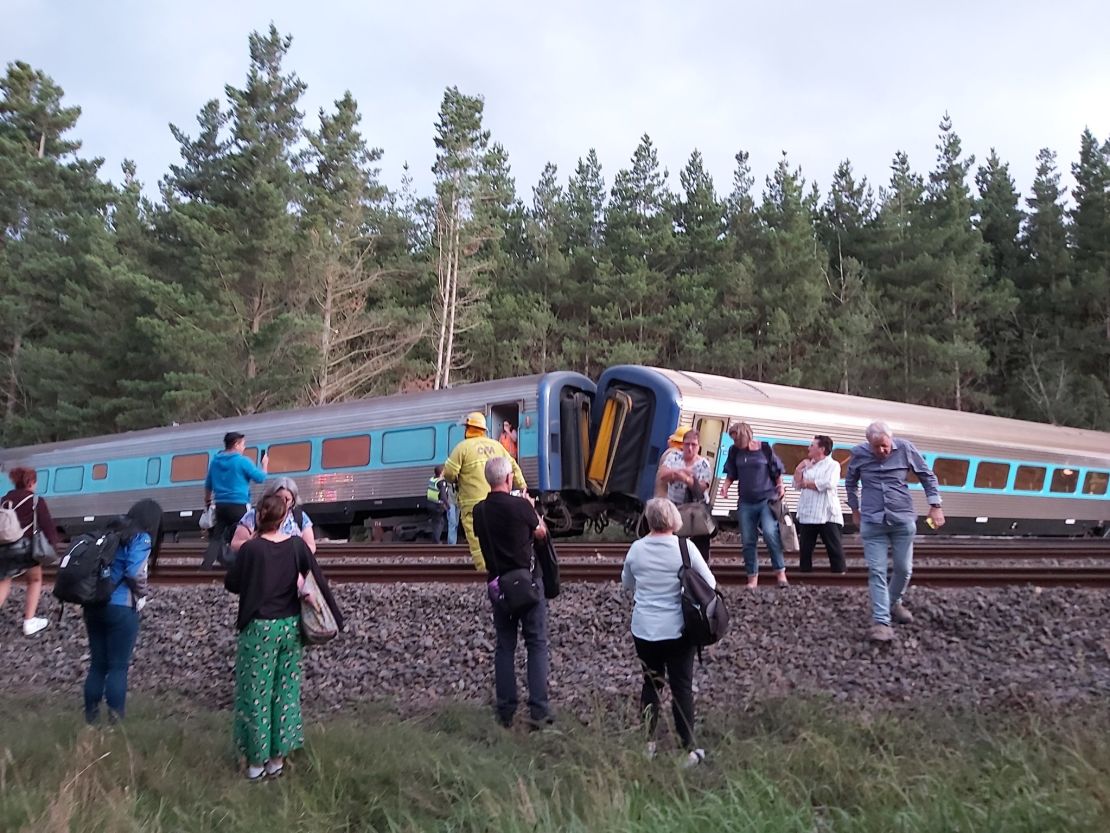 Passengers surround the derailed train.