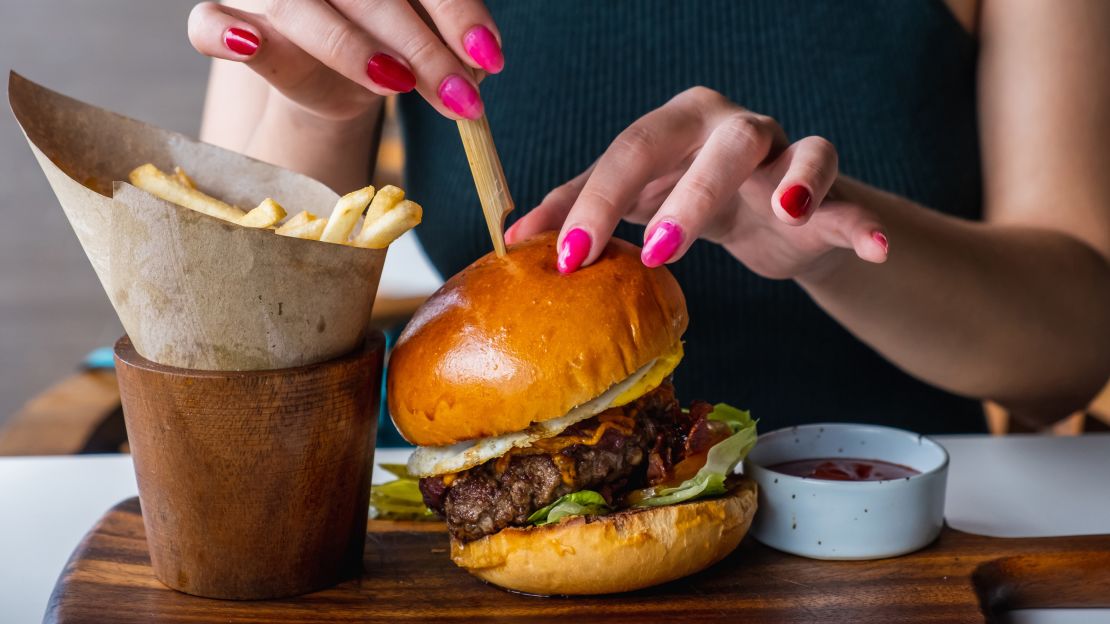 Person eating a cheeseburger and fries.