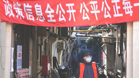 A man in Shanghai wears a mask amid the novel coronavirus outbreak, under a sign proclaiming "open information, just and equitable."