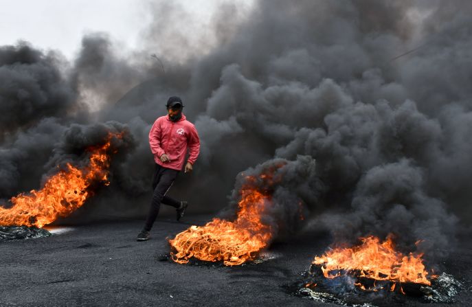 A man runs past burning tires during an anti-government protest in Nasiriyah, Iraq, on Sunday, February 16.