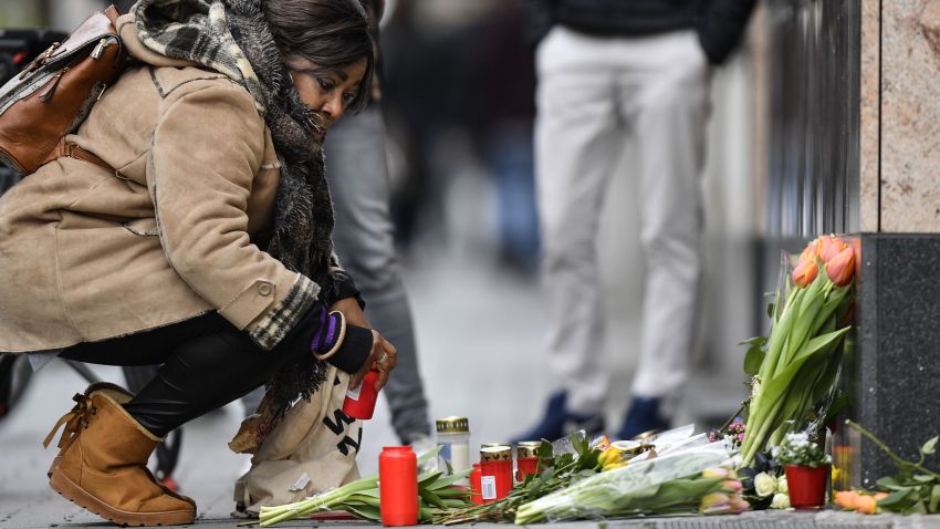 A woman sets a candle near the hookah bar scene where several people were killed late Wednesday in Hanau, Germany, Thursday, Feb. 20, 2020.  A 43-year-old German man shot and killed several people at different locations in a Frankfurt suburb overnight in attacks that appear to have been motivated by far-right beliefs, officials said Thursday. (AP Photo/Martin Meissner)