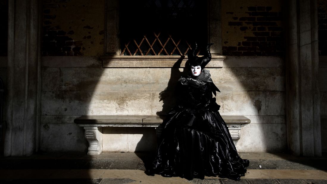 <strong>Venice, Italy:</strong> A woman wearing a Carnival costume sits on a bench of the Palazzo Ducale on Sunday, February 16.