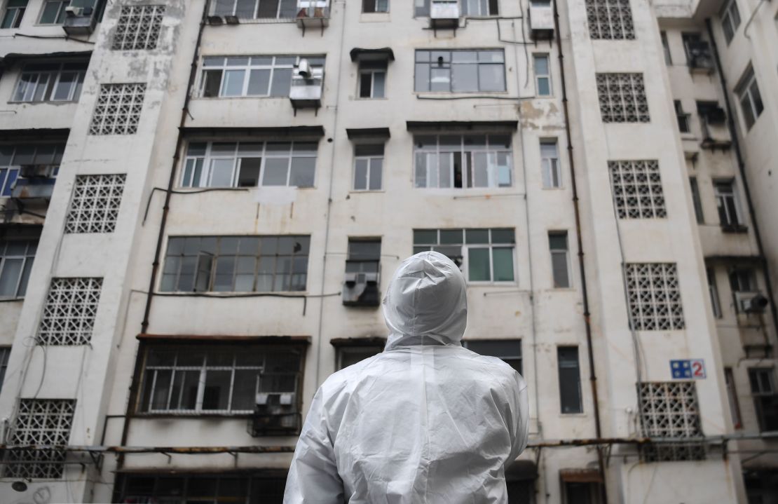 A community worker stands in front of a residential building as he prepares to conduct a health check in Caidian District of Wuhan.
