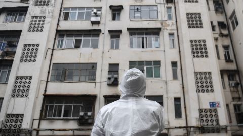 A community worker stands in front of a residential building as he prepares to conduct a health check in Caidian District of Wuhan.
