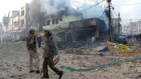 Policemen stand in front of burned shops in New Delhi following clashes over a new citizenship law on February 24.
