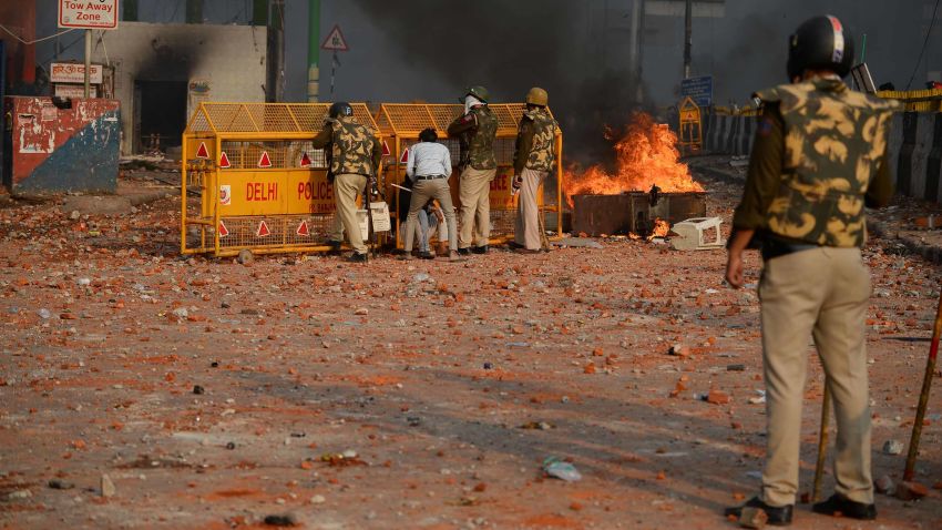 Policemen shelter behind a barrier in a road scattered with stones following clashes between supporters and opponents of a new citizenship law, at Bhajanpura area of New Delhi on February 24, 2020, ahead of US President arrival in New Delhi. - Fresh clashes raged in New Delhi in protests over a contentious citizenship law on February 24, hours ahead of a visit to the Indian capital by US President Donald Trump. India has seen weeks of demonstrations and violence since a new citizenship law -- that critics say discriminates against Muslims -- came into force in December. (Photo by Sajjad HUSSAIN / AFP) (Photo by SAJJAD HUSSAIN/AFP via Getty Images)
