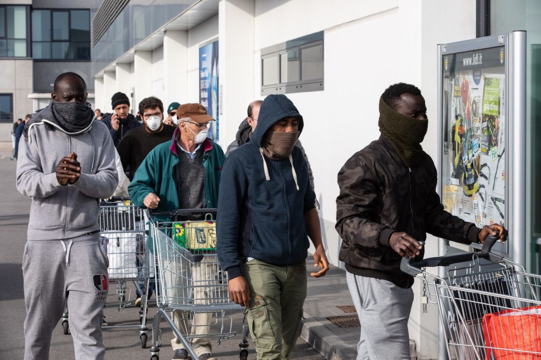 People wearing respiratory masks wait to get into a supermarket in Casalpusterlengo, southeast of Milan, on Sunday.