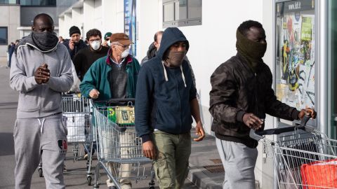 People wearing respiratory masks wait to get into a supermarket in Casalpusterlengo, southeast of Milan, on Sunday.